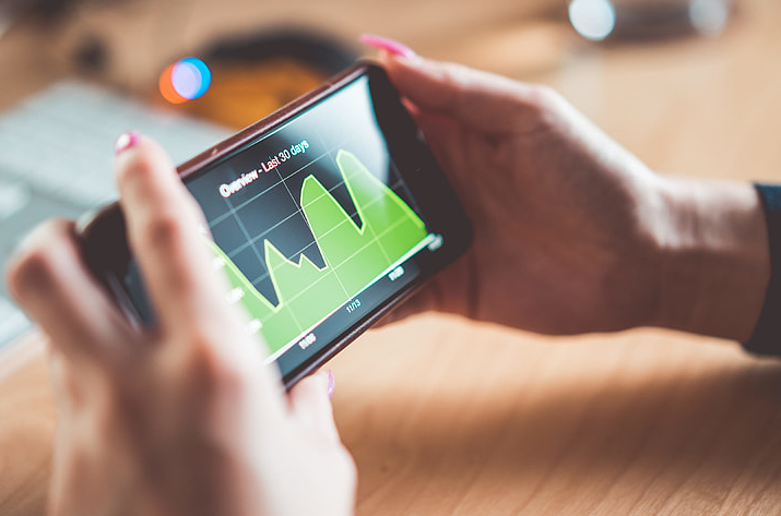 Close-up of hands holding a smartphone displaying analytics data for an online business.